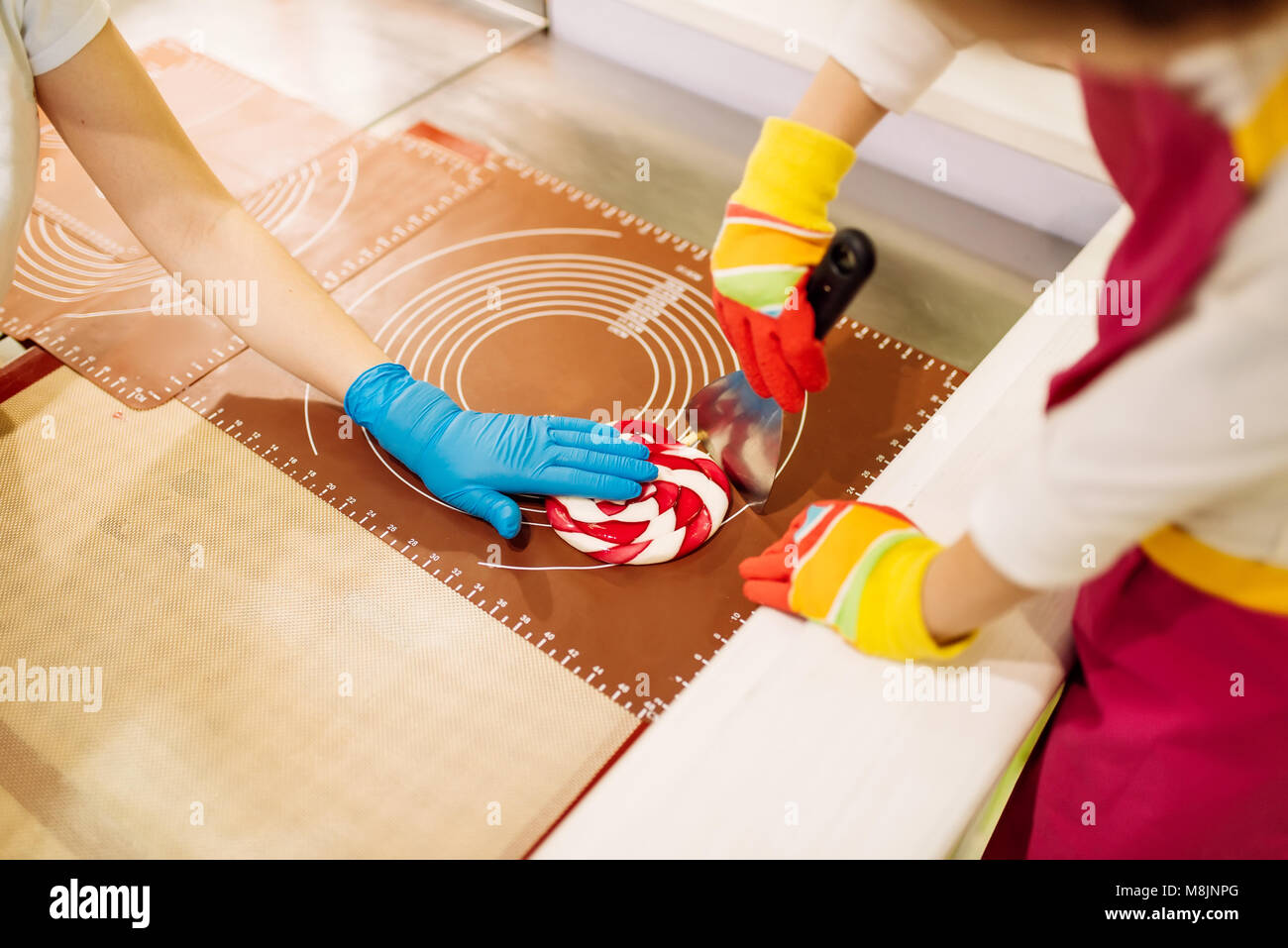 Lecca-lecca processo di preparazione, bambino fa confetti al caramello in officina. Vacanze e divertimento nel negozio di caramelle Foto Stock