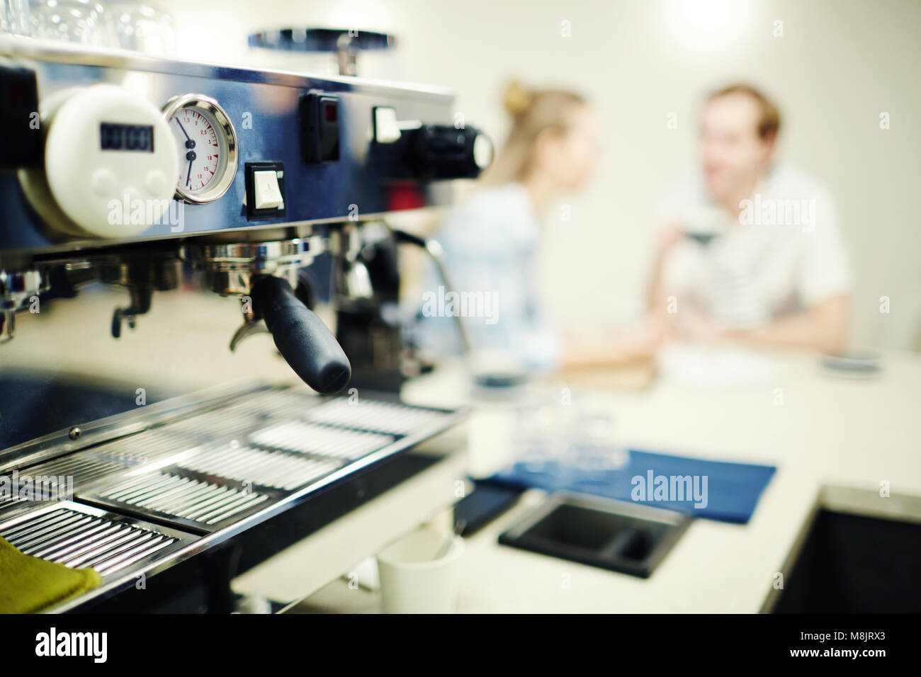 Close-up di caffè lavorato in coffee shop con persone in background Foto Stock