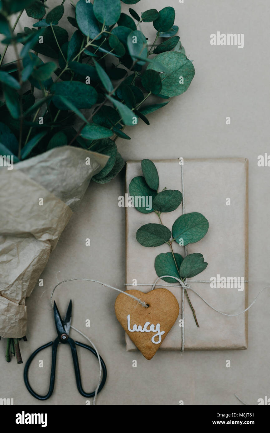 Impacchettare i regali di Natale con la carta normale e pan di zenzero i biscotti con lo zucchero a velo su di essi Foto Stock