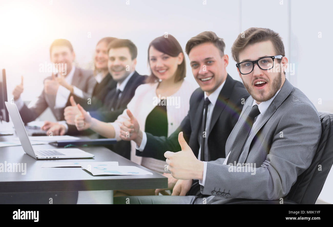 Il team di business con il pollice in su mentre è seduto alla sua scrivania Foto Stock