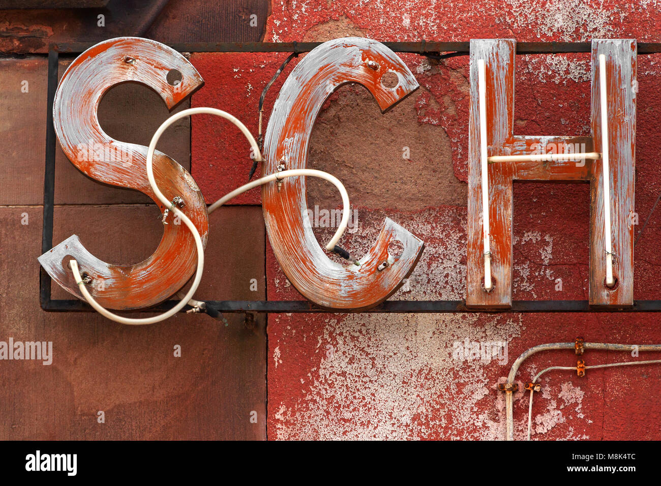 Dettaglio di un neon di run-all'insegna al neon, lettere e sfondo rossastra. Tubi al neon. 3 lettere. Tubi al neon dei primi due sono staccati dalla base. Foto Stock