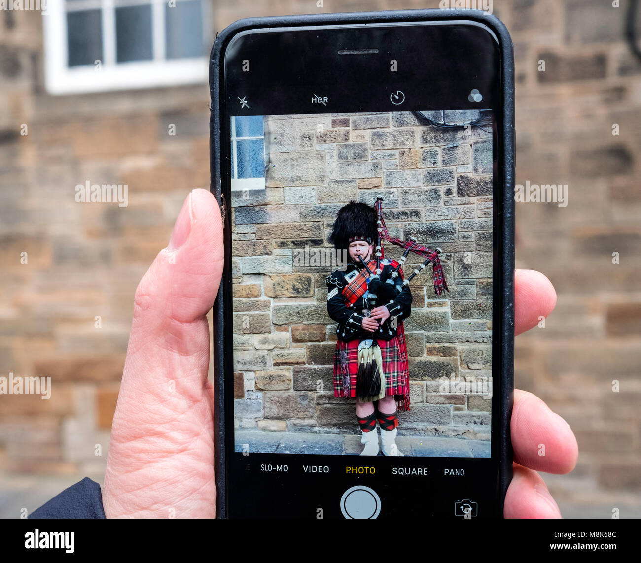 Turistica prendendo foto di uomo scozzese in tartan la riproduzione di cornamuse sul Royal Mile di Edimburgo Città Vecchia, Scotland, Regno Unito Foto Stock