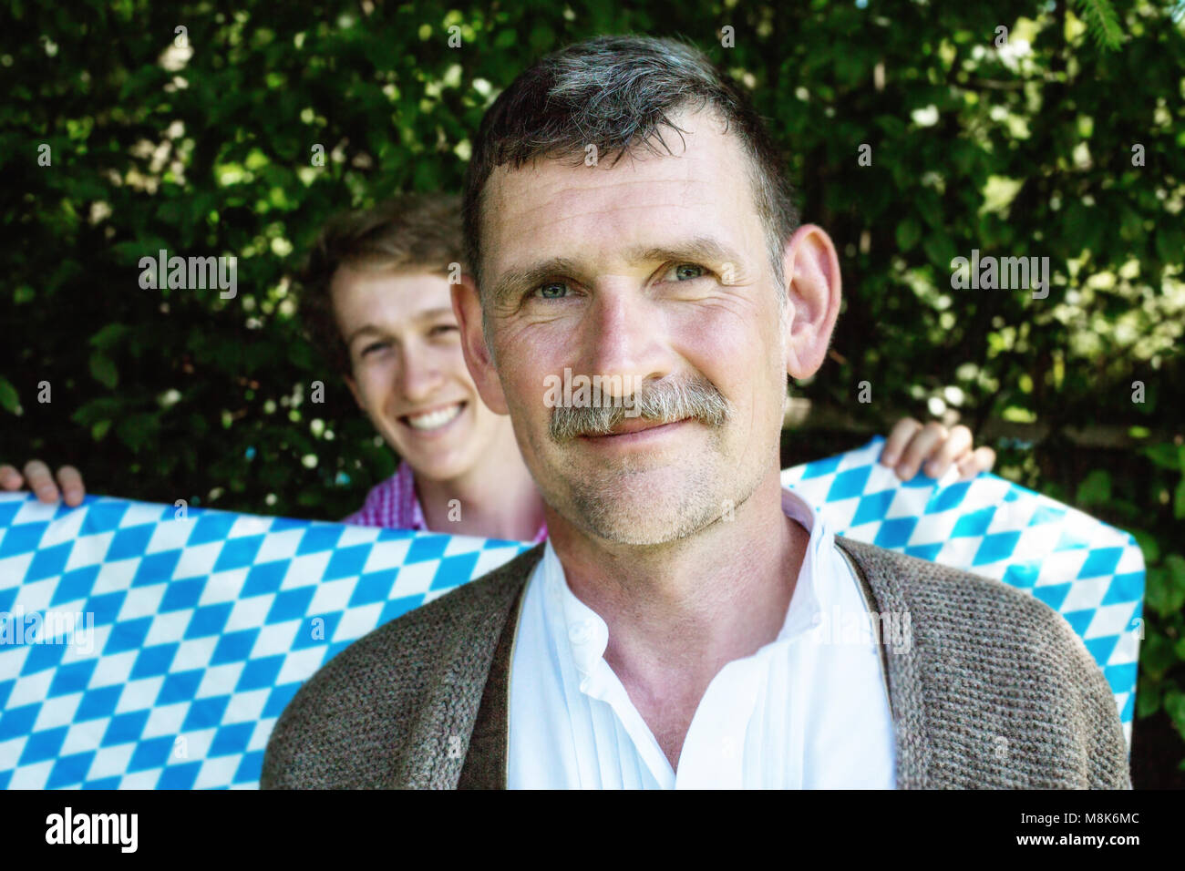 Ritratto di bello uomo vecchio e giovane azienda fino la bavarese di colori blu e bianco Foto Stock