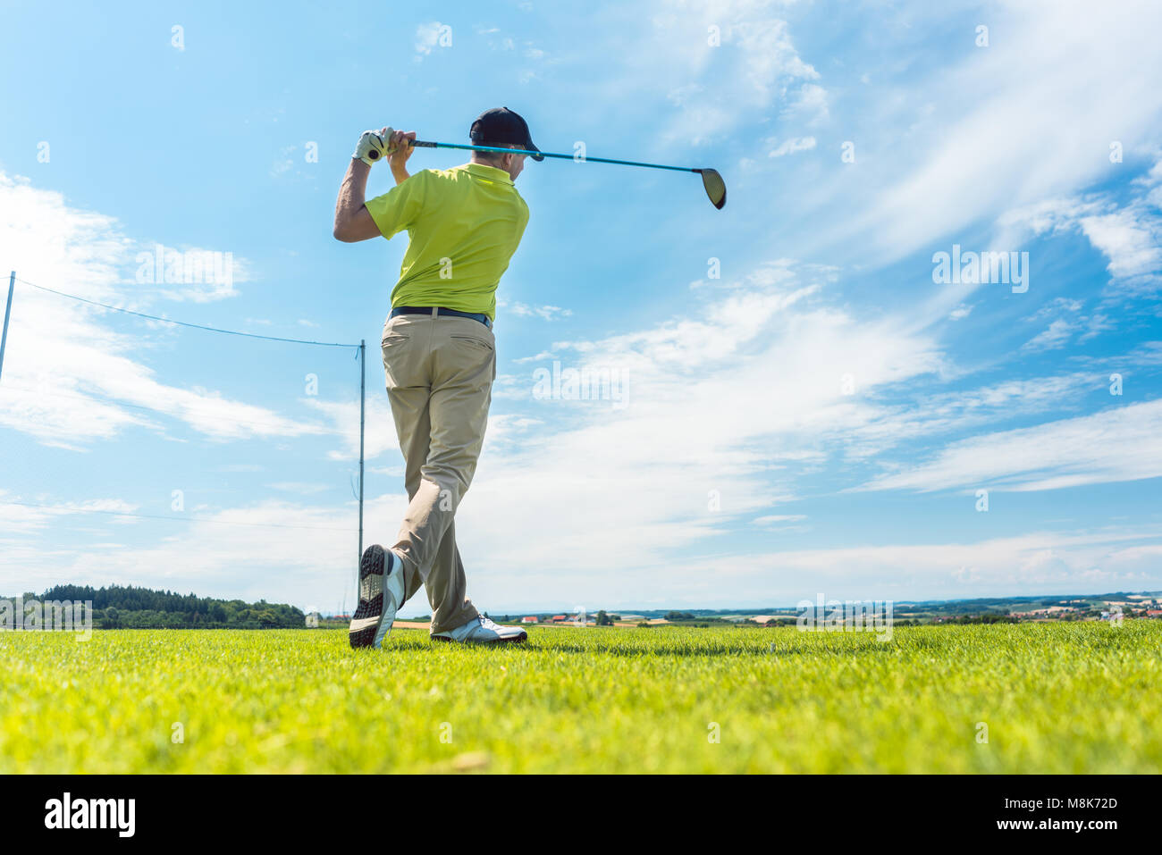 L uomo nella posizione finale di una oscillazione di guida mentre giocando a golf Foto Stock