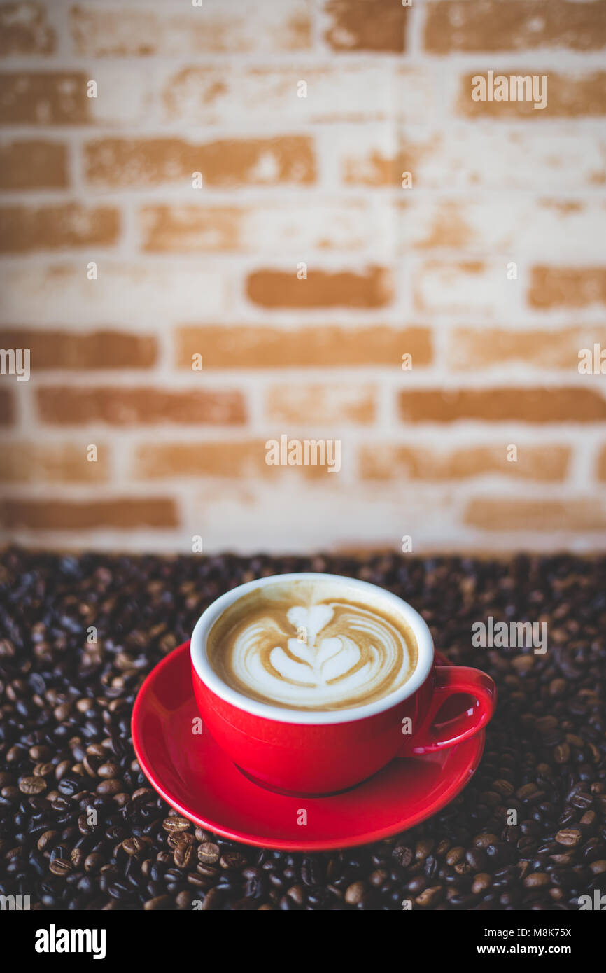Un rosso tazza di caffè con chicco di caffè Foto Stock