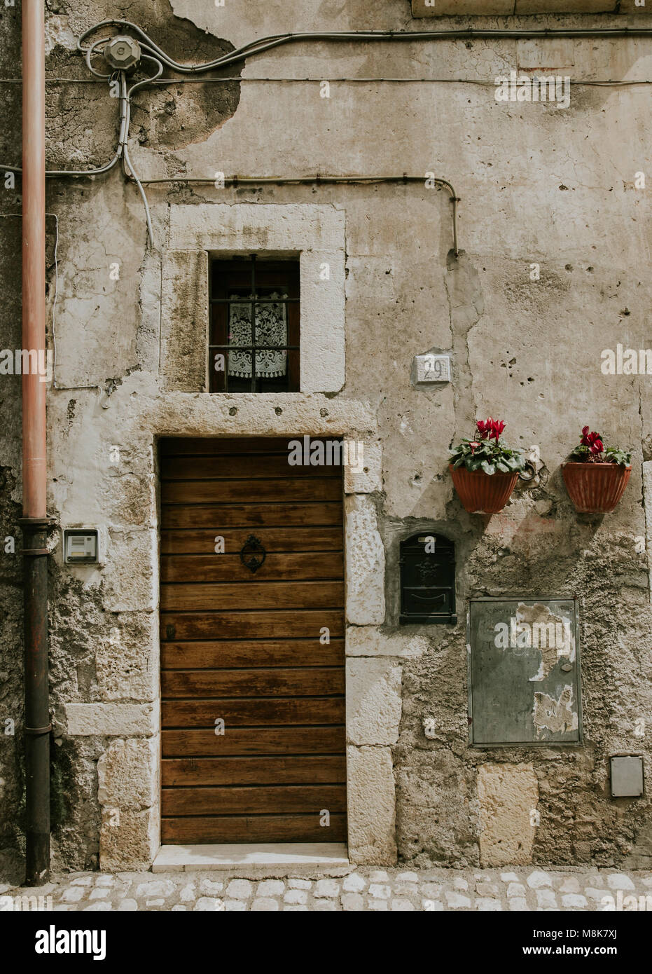Italiano porta anteriore con piccola finestra e fiori sulla parete di ingresso Foto Stock