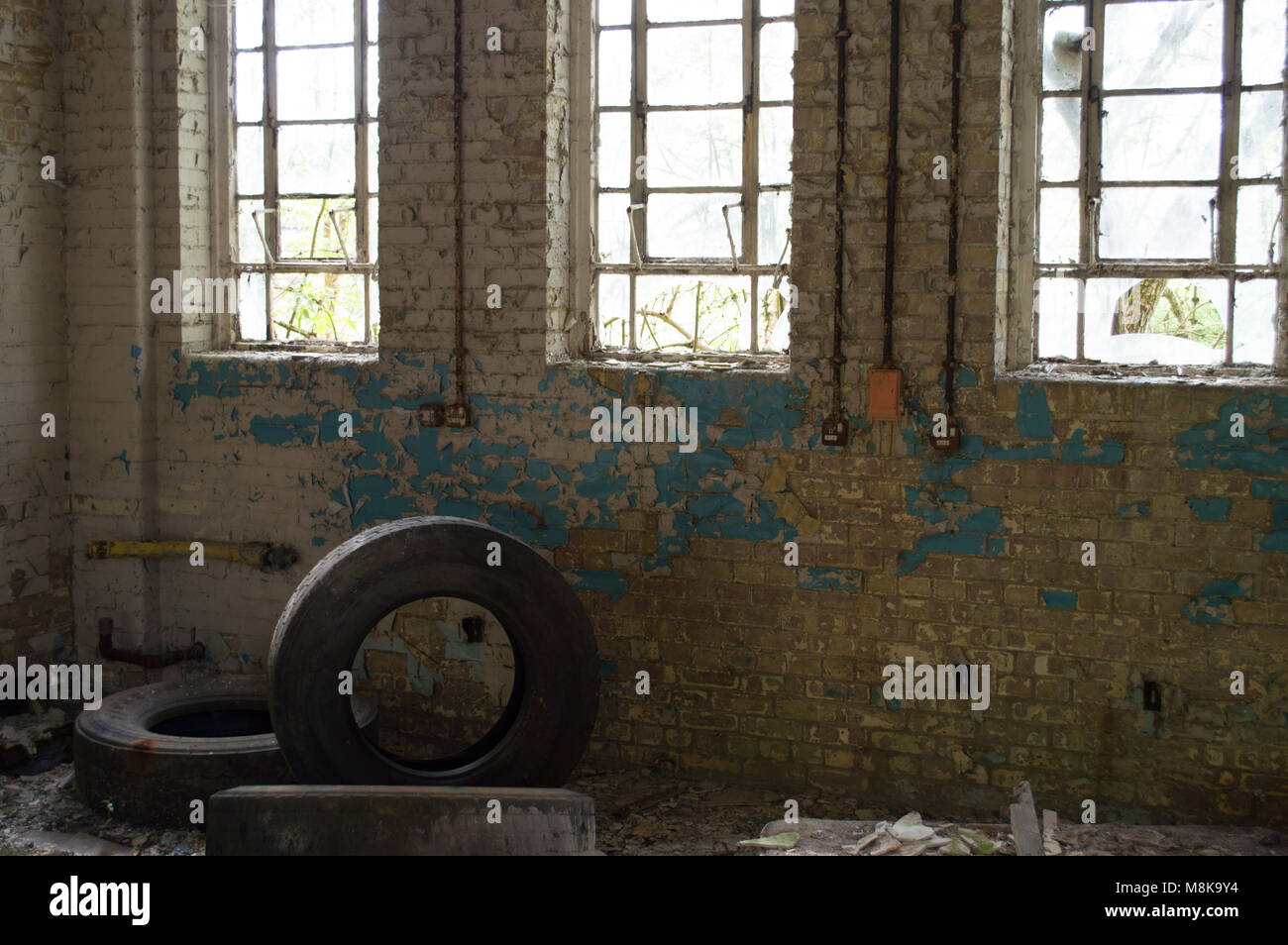 Un vecchio edificio abbandonato con le finestre rotte, peeling vernice e tre pneumatici usati. Foto Stock