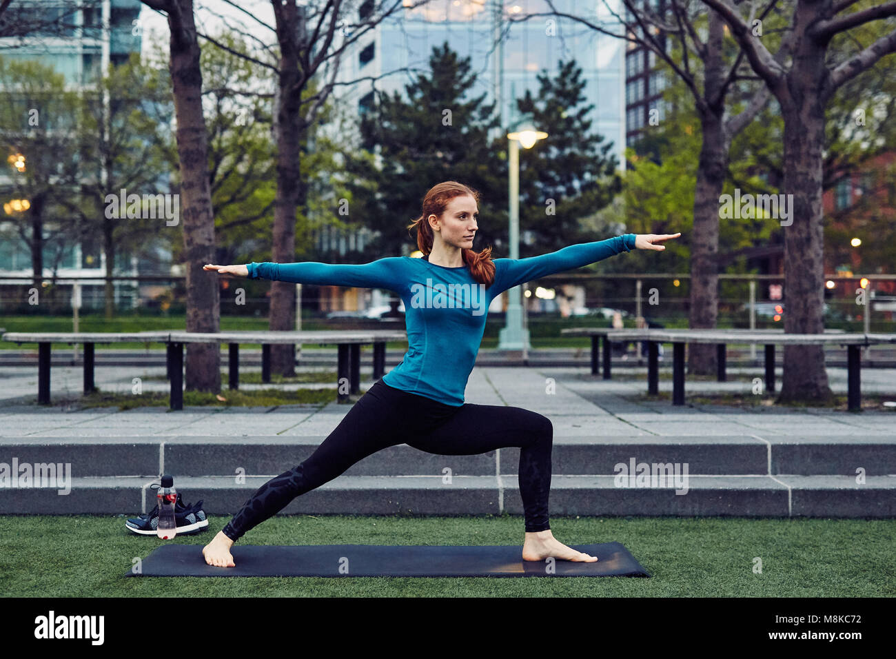 La donna caucasica esegue lo Yoga in un pubblico di New York City Park Foto Stock