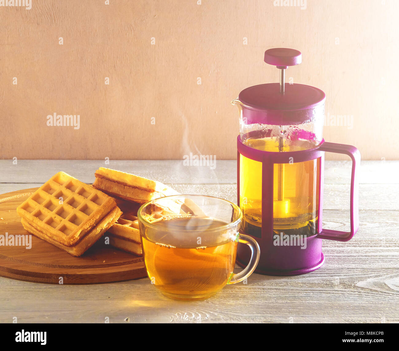 Waffles fatti in casa con la marmellata sul vecchio tavolo in legno. Wafers con tazza di tè con teiera. Foto Stock