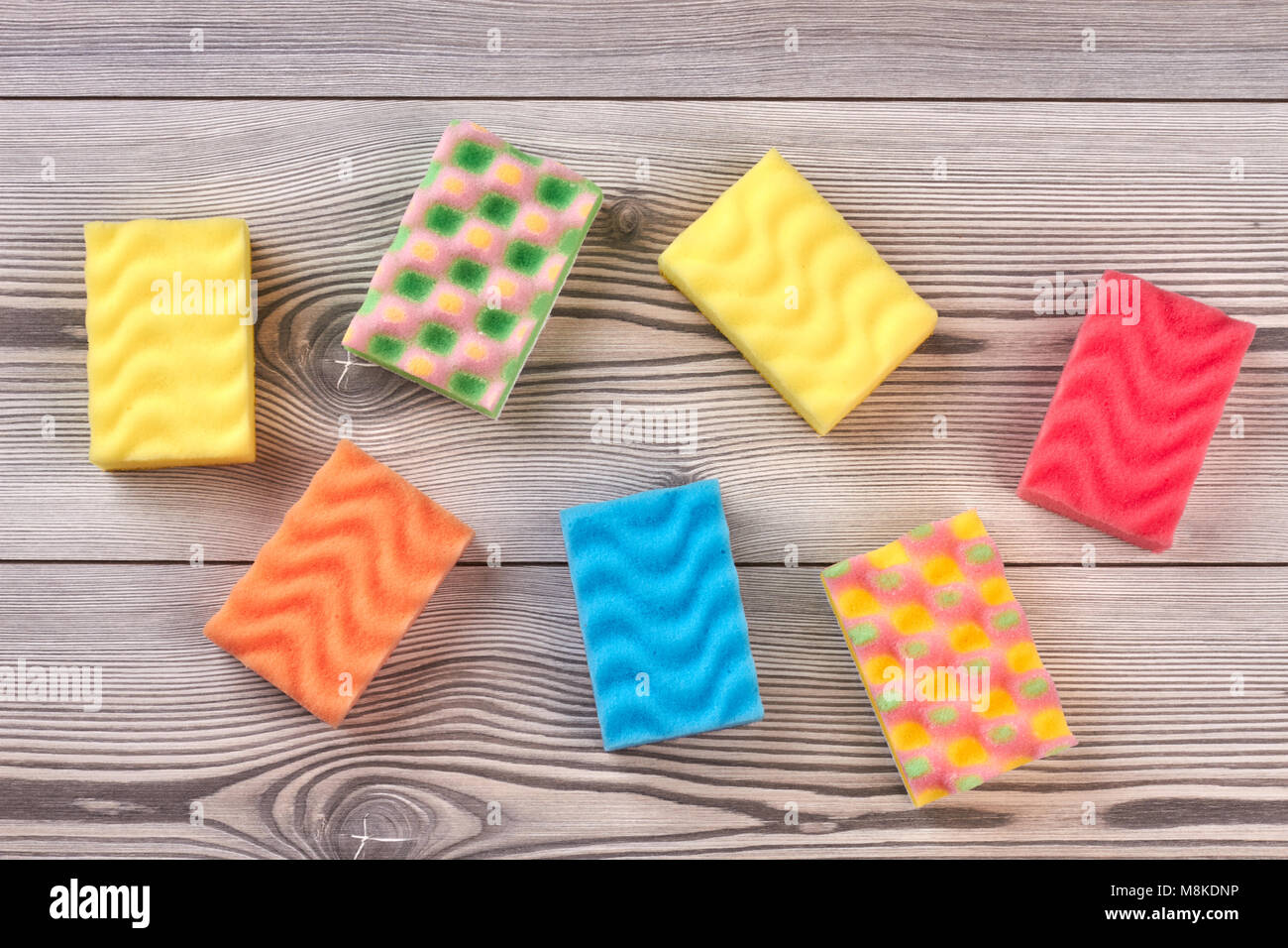 Variopinte spugne cucina, sullo sfondo di legno. Foto Stock