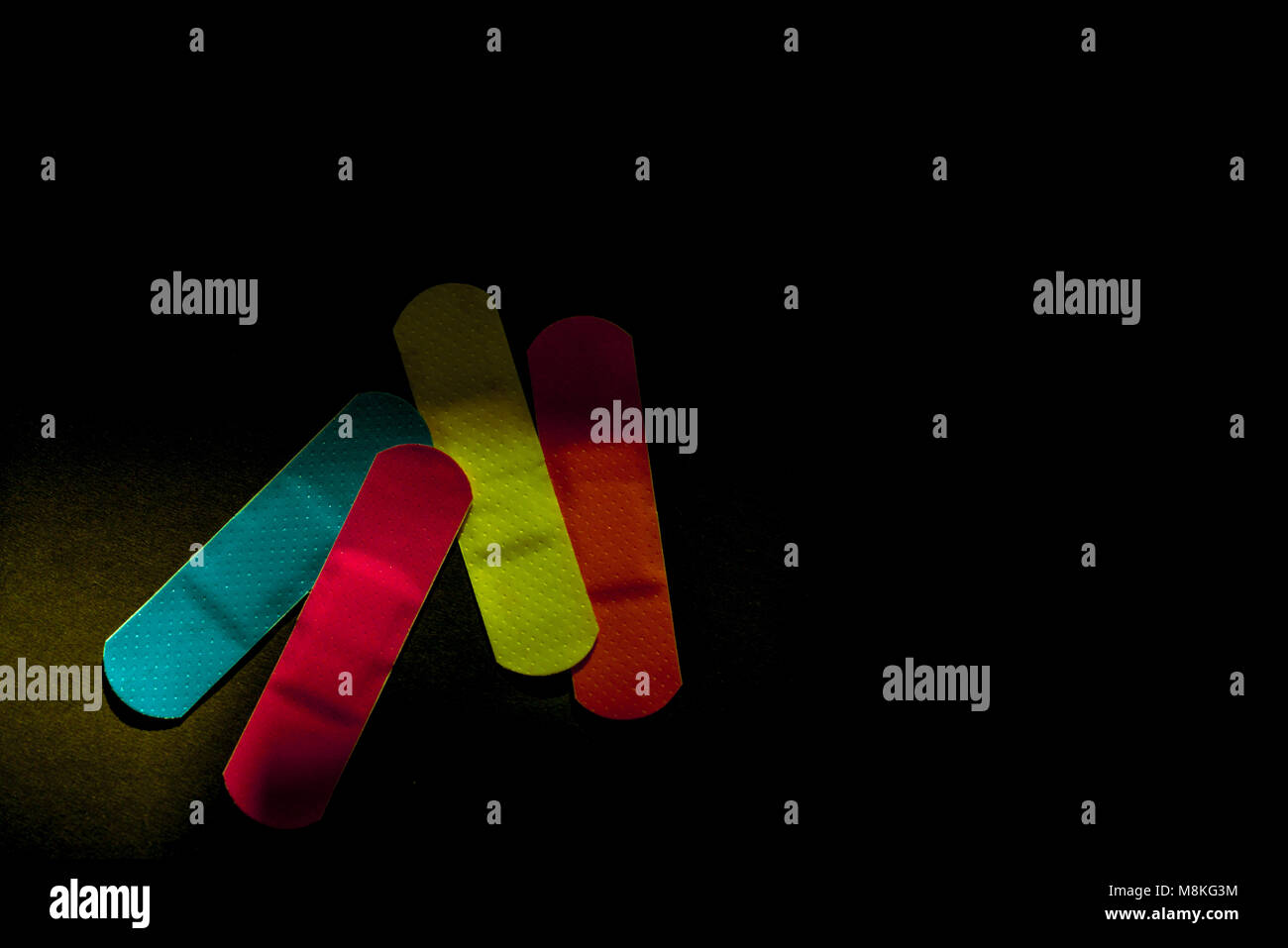 Primo soccorso medicazione (intonaco) con non-stick pad per la rapida guarigione della ferita su sfondo scuro con copia spazio. Sterile medicazione di ferita con colori luminosi i Foto Stock