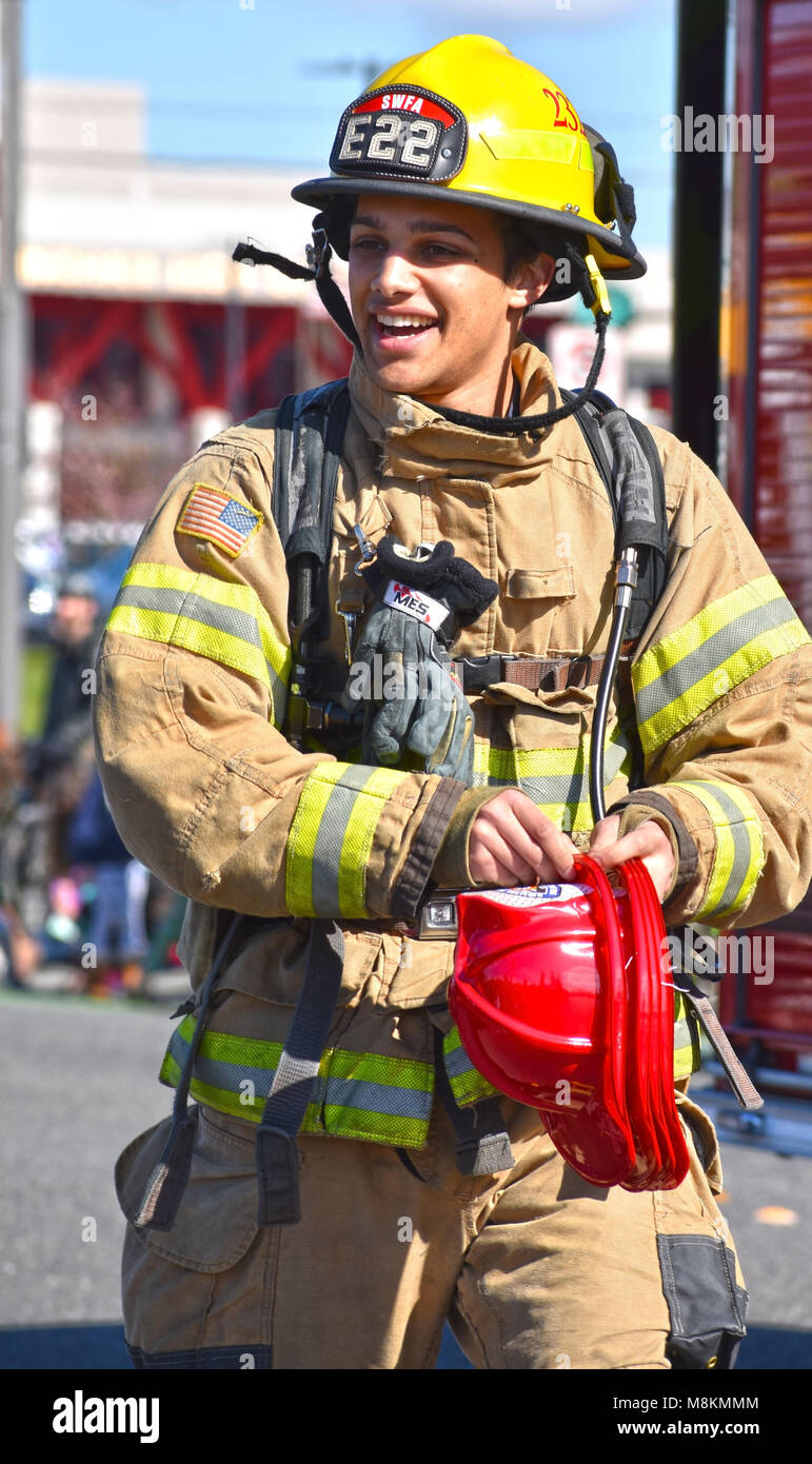 Un vigile del fuoco nella festa di San Patrizio Parade di Bellingham, Washington il 17 marzo 2018. Il vigile del fuoco è dare il rosso fuoco cappelli. Foto Stock