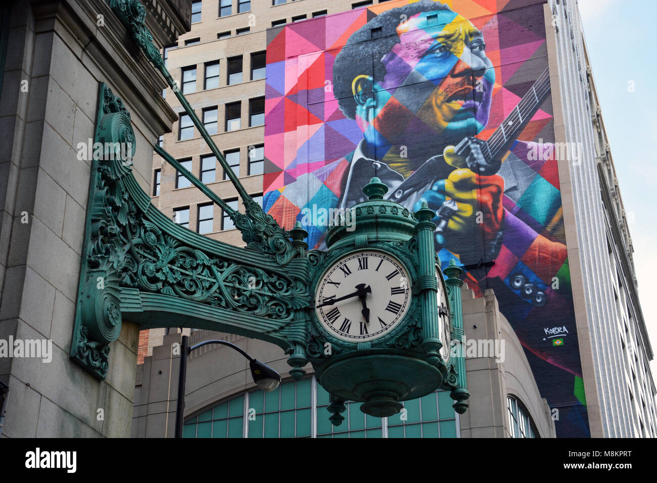 Oltre cento-anno-vecchio Marshall Fields orologi e un più recente murale di Blues grandi acque fangose su State Street a Chicago. Foto Stock