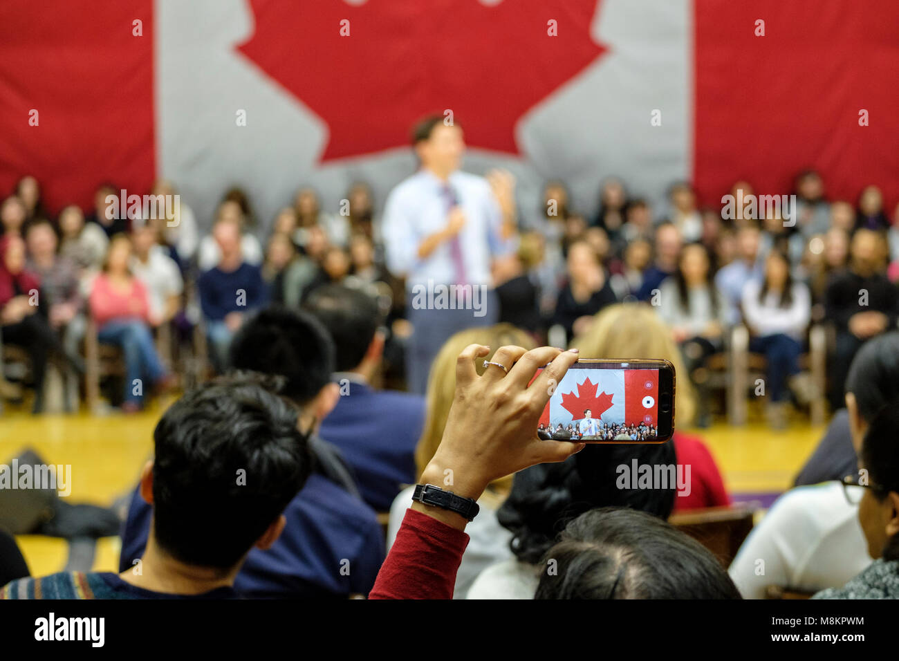 La mano di una donna in possesso di un cellulare per scattare una foto di Justin Trudeau, primo ministro del Canada, in corrispondenza di un municipio riunione a Londra, Ontario, Canada. Foto Stock