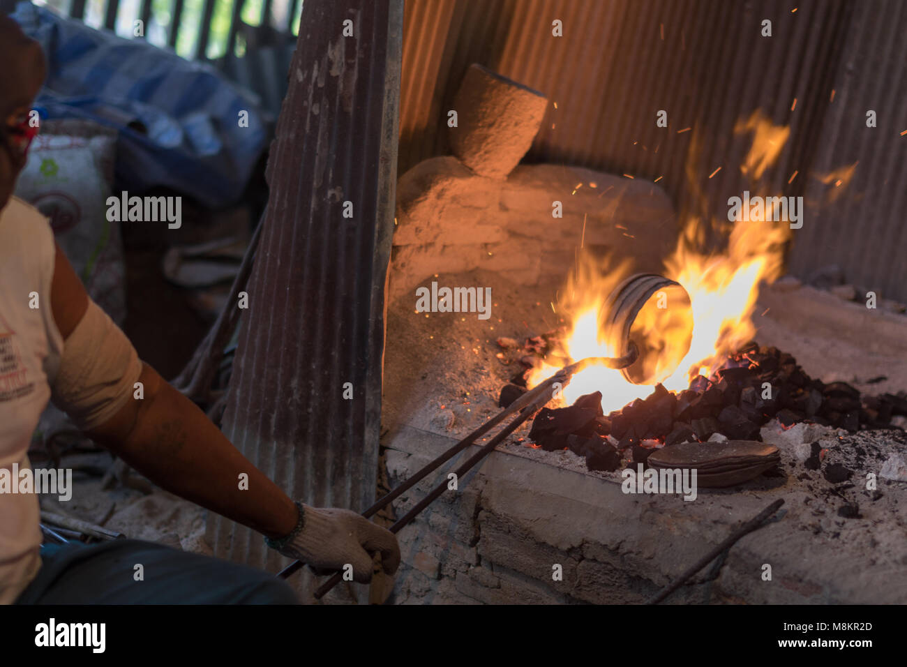L'uomo che fa le ciotole di ottone sopra i carboni caldi. Foto Stock