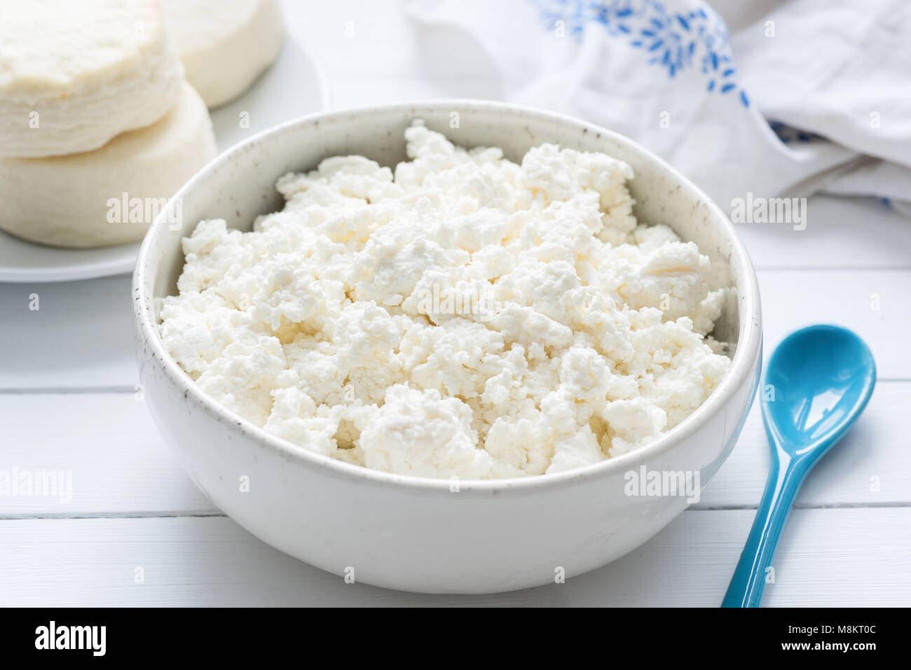 Tvorog, agricoltori, formaggio di ricotta o formaggio nella ciotola bianco su bianco tavolo in legno, primo piano. Ricca in calcio cibo sano Foto Stock