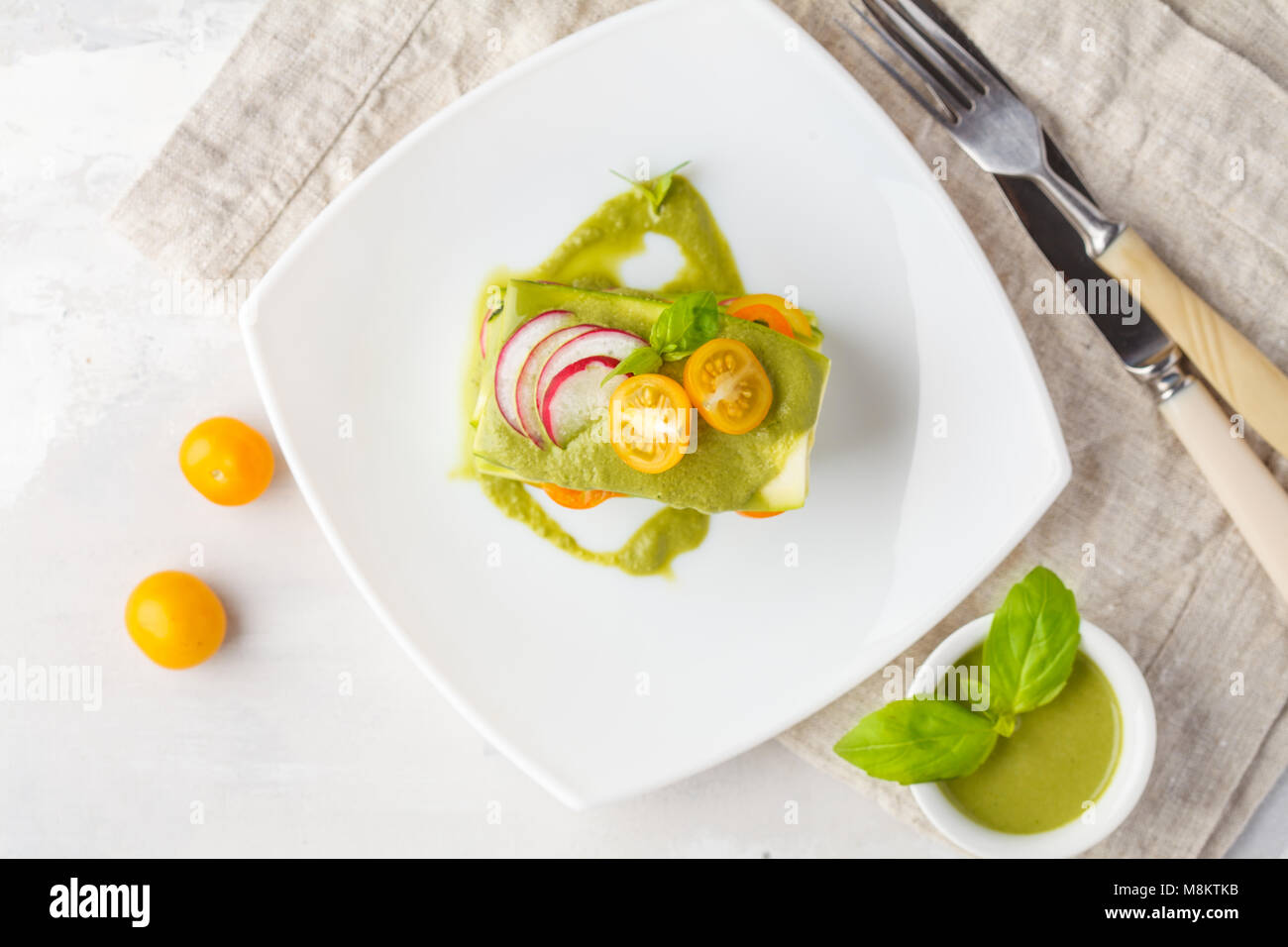 Materie zucchine lasagne con verdure e pesto, sfondo luminoso. Vegetariano crudo concetto di dieta. Foto Stock