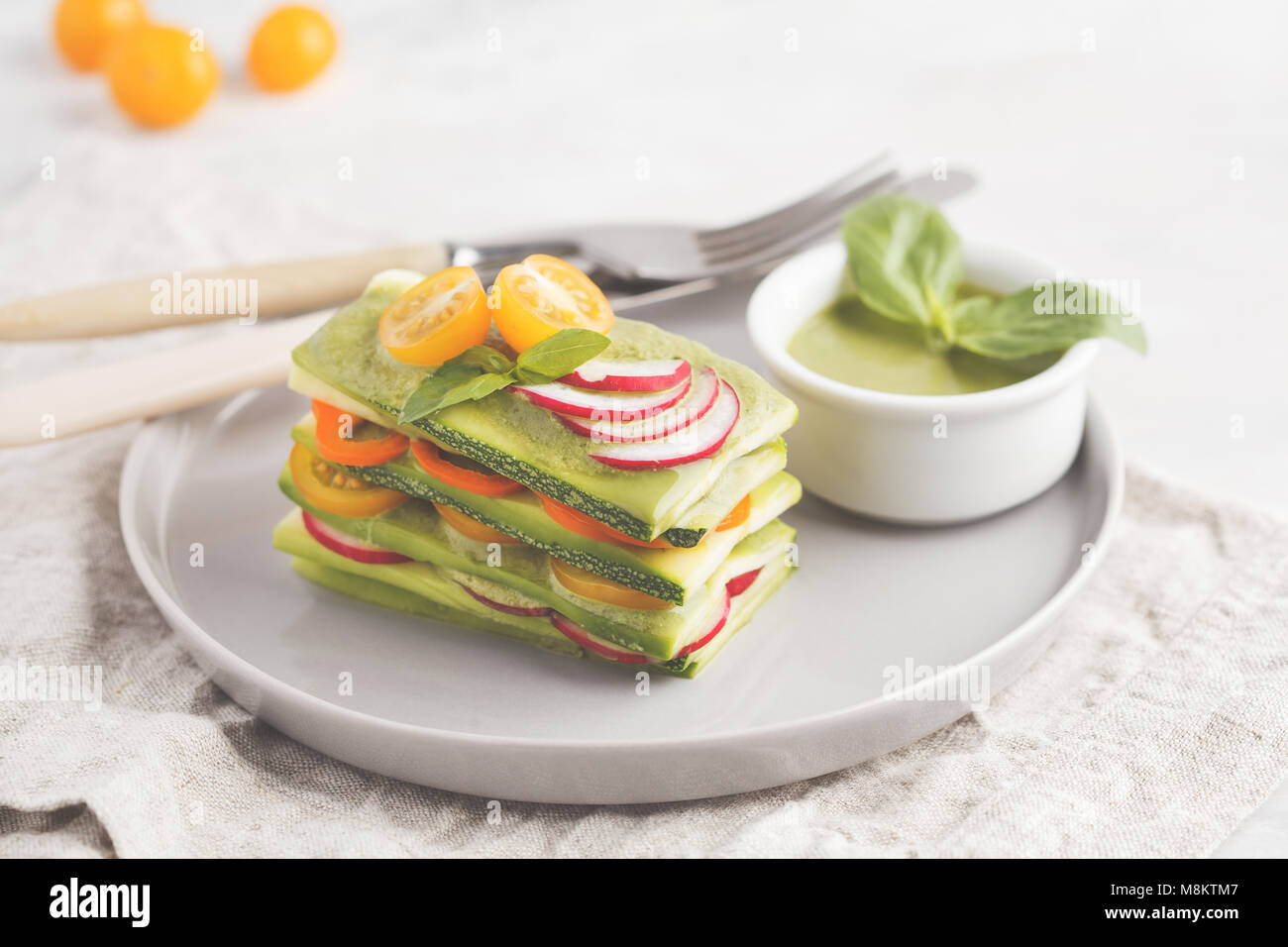 Materie zucchine lasagne con verdure e pesto, sfondo luminoso. Vegetariano crudo concetto di dieta. Foto Stock