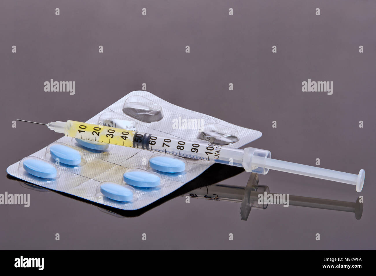 Pillole, siringa e ago su sfondo grigio. Concetto medico Foto Stock