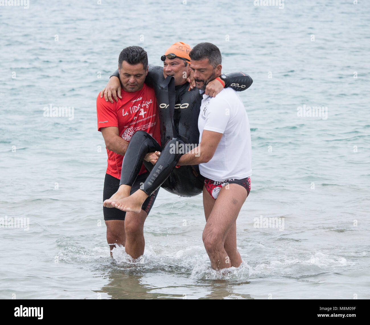 Un triatleta disabili è aiutato dall'acqua dopo aver completato la nuotata gamba del triathlon sprint all'ETU European Cup triathlon su Gran Canaria Foto Stock