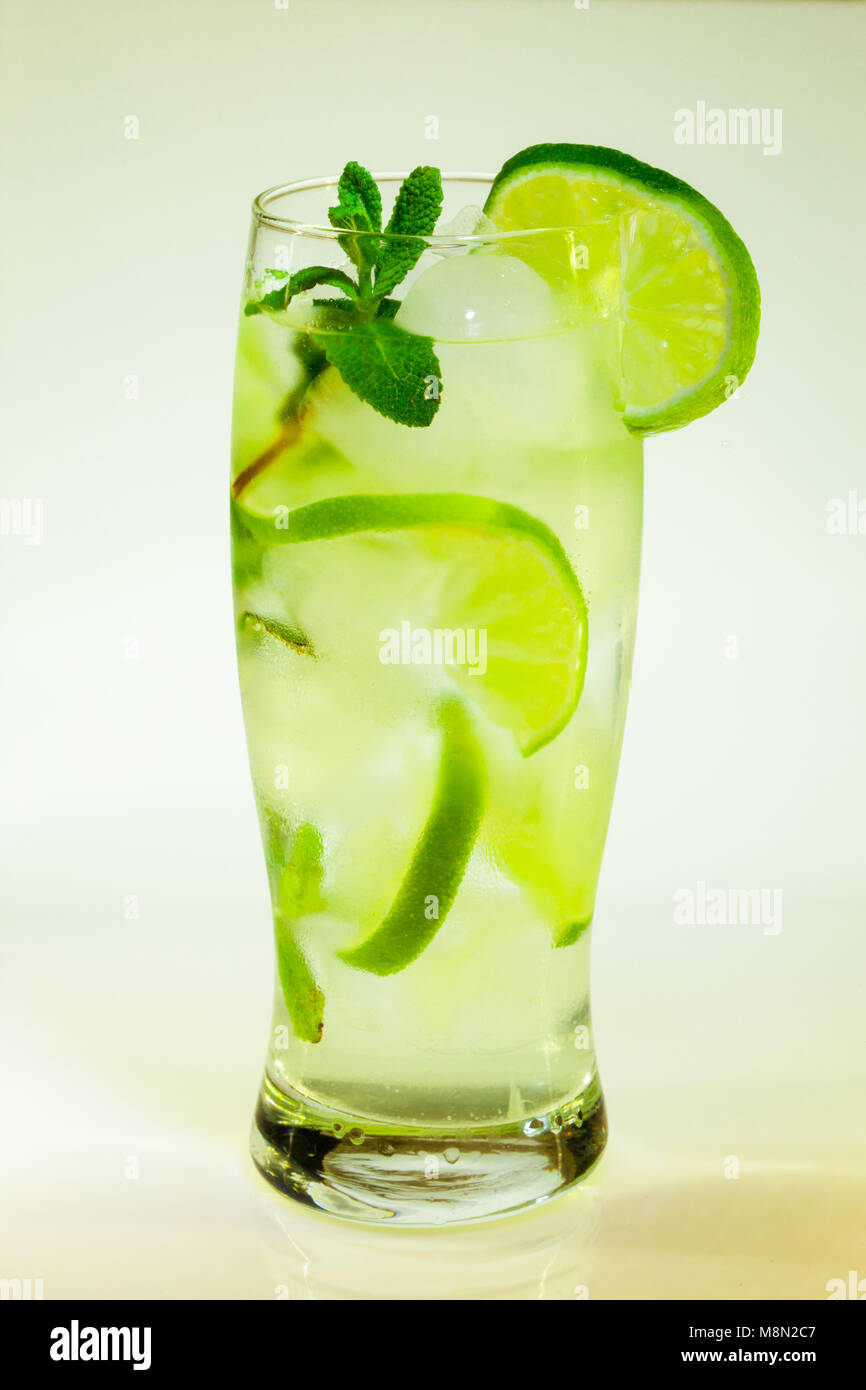 Estate bevanda fredda mojito lime e menta con ghiaccio e soda con gocce su un vetro su uno sfondo bianco Foto Stock