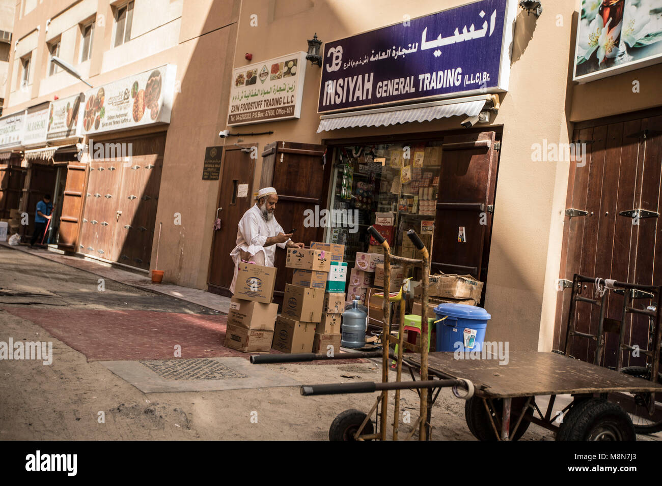 Uomo con merci nella parte anteriore di un general trading store sulla strada di Dubai, Emirati arabi uniti Foto Stock