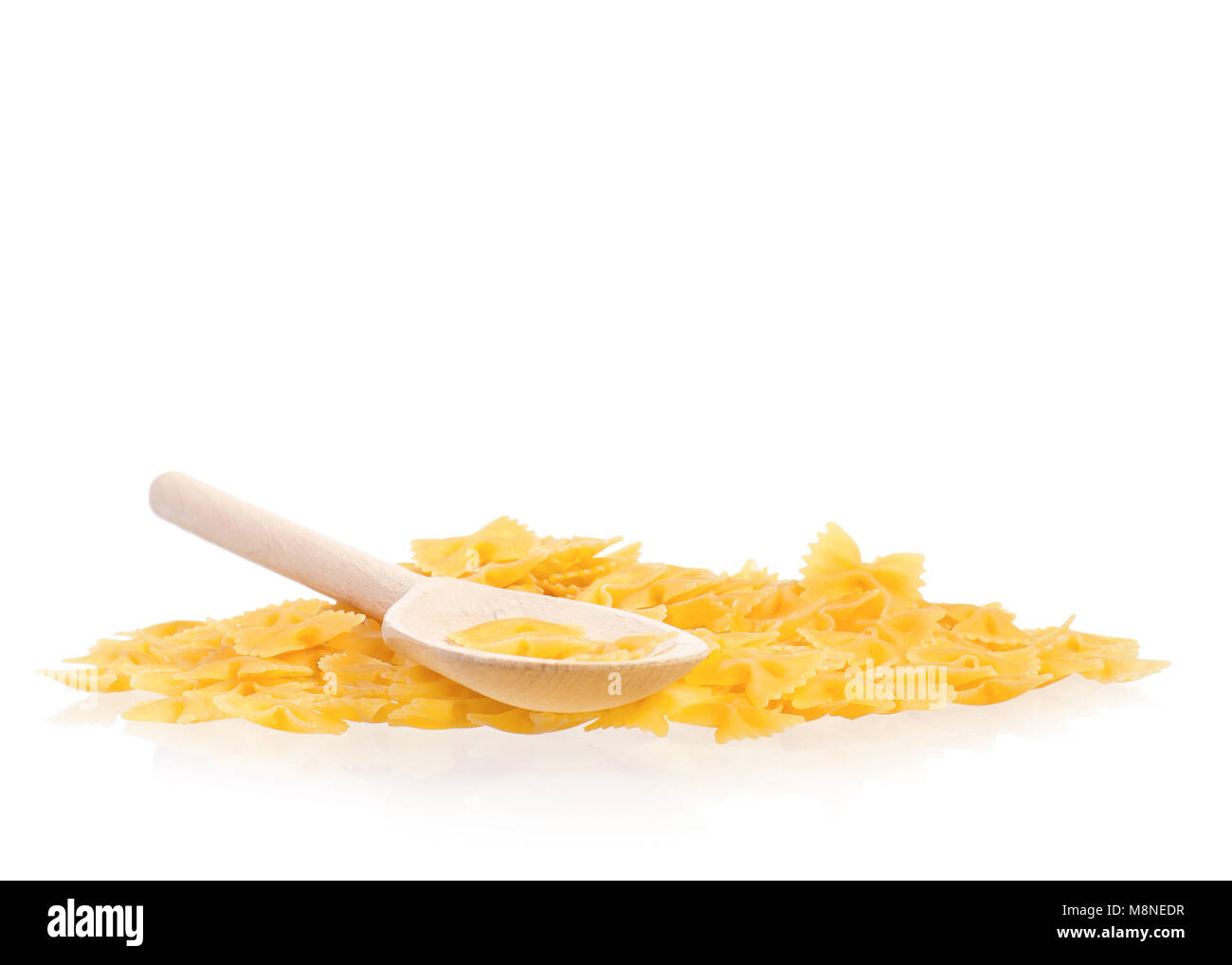 Cucchiaio di legno secco con pasta di colore giallo isolato su sfondo bianco. Non cotti italiano la pasta grezza. Foto Stock