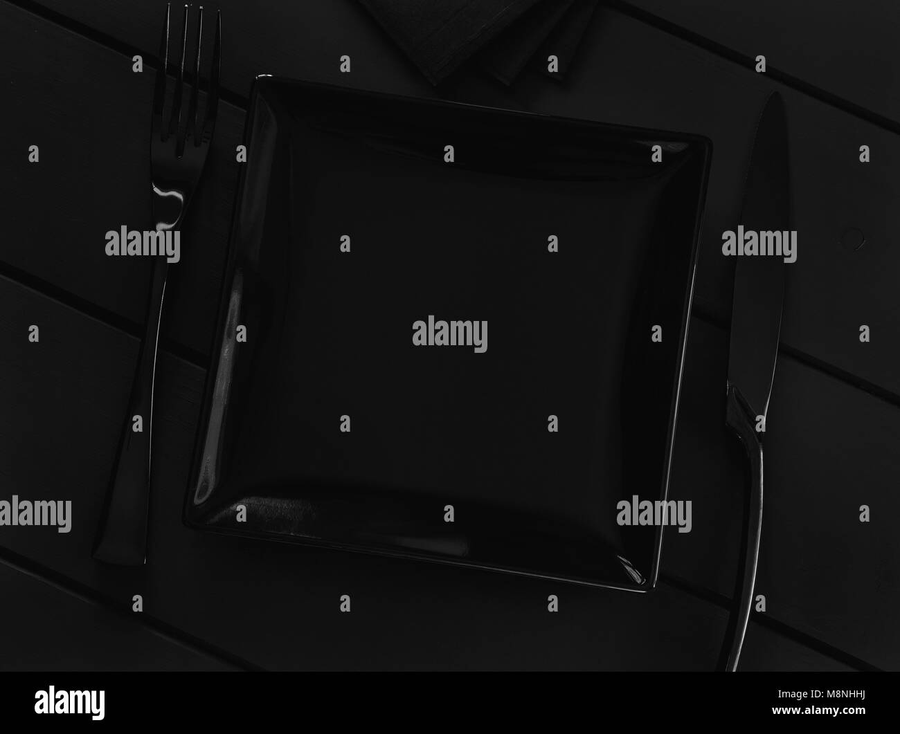 Nero piastra vuota e posate su una tavola nera Foto Stock