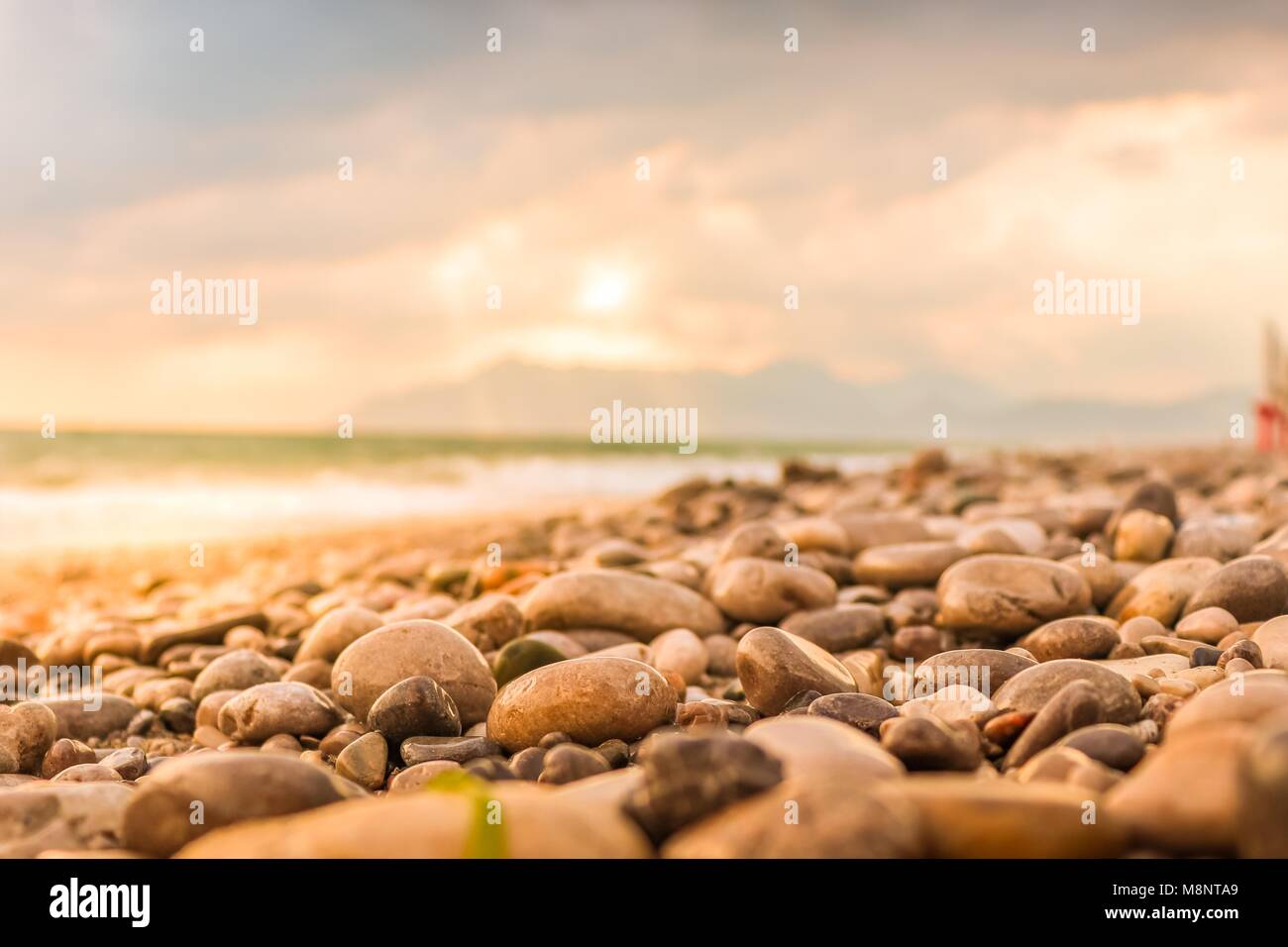 Wet round pietre lucenti in estate spiaggia vuota closeup con mare, montagne e nuvoloso colorate sullo sfondo del cielo. Salerno, a sud di Italia Foto Stock