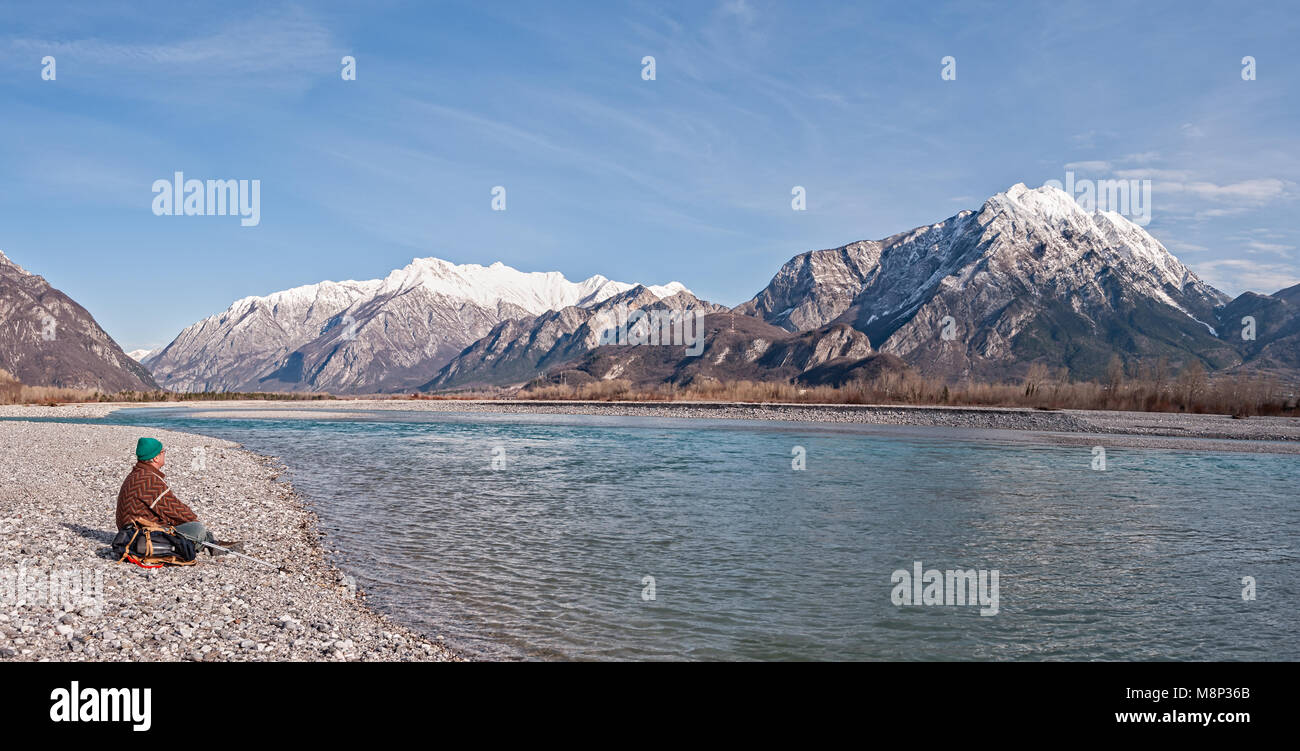 L'uomo escursionista gode di vista sul fiume e sulle montagne. Alpi italia Friuli Venezia Giulia. Foto Stock