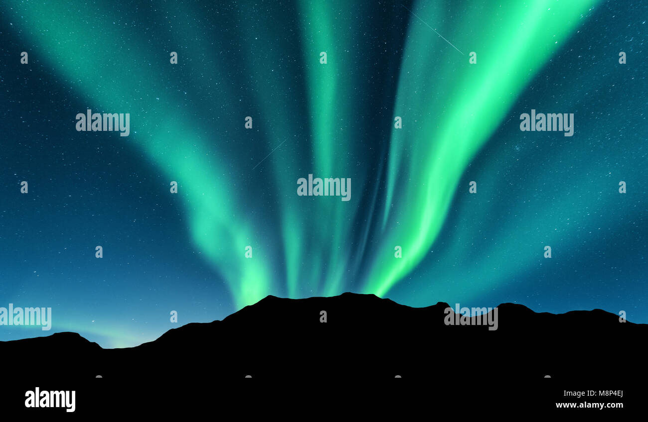 Aurora e silhouette di montagne. Isole Lofoten in Norvegia. Aurora Boreale. Green luci del nord. Cielo con le stelle e le luci polari. Paesaggio notturno Foto Stock