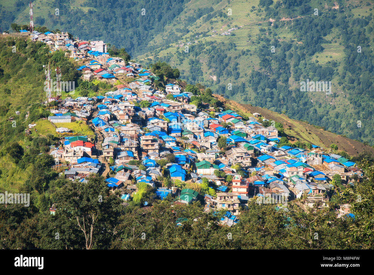 Bel paesino sulla montagna al tramonto. Paesaggio colorato con case con tetti blu, alberi, montagna con bosco verde in Nepal. Rustico Foto Stock