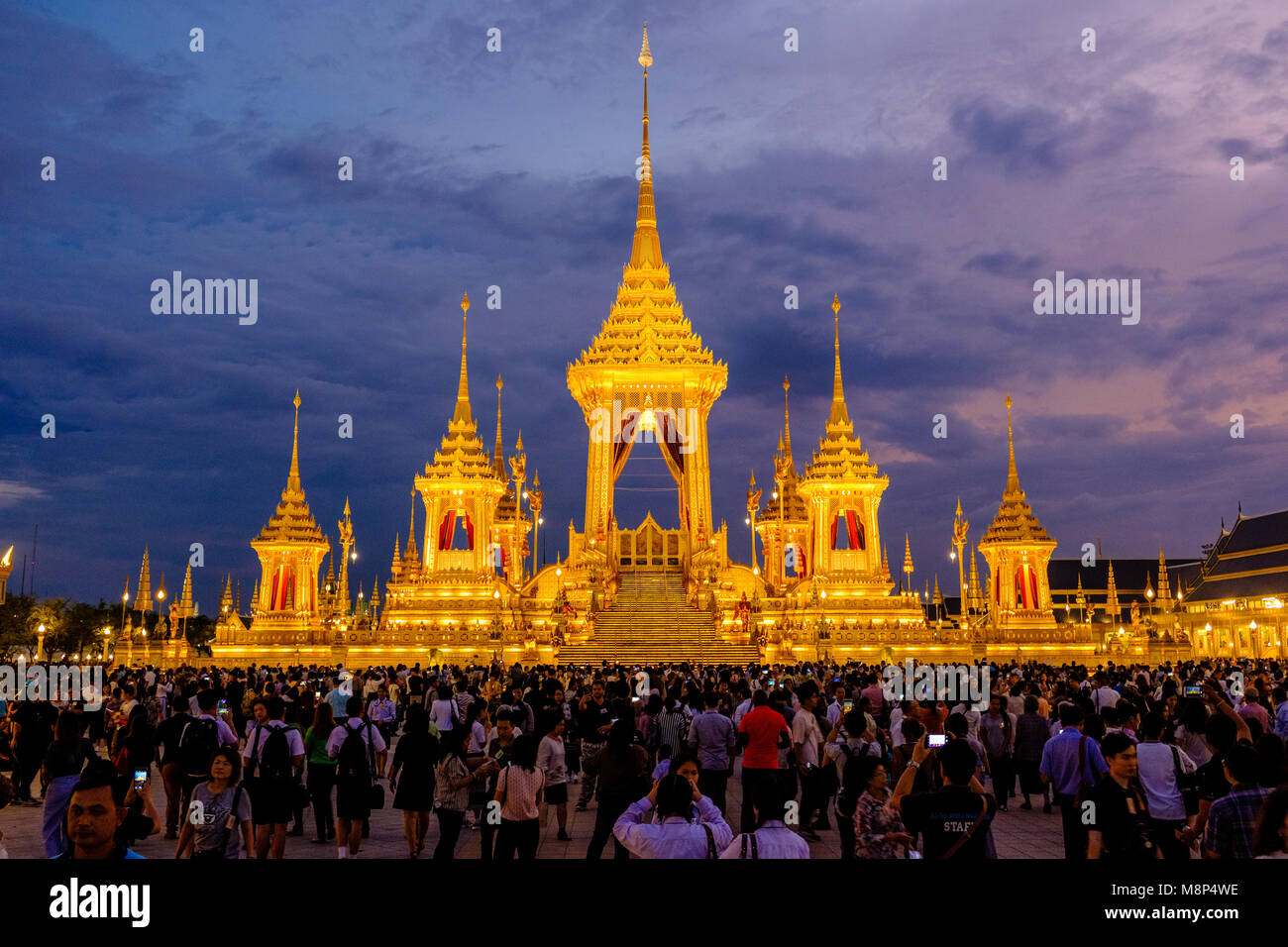 Persone in lutto sedersi di fronte al royal illuminato crematorio e complesso funebre dopo la morte del re Bhumibol Adulyadej di notte Foto Stock