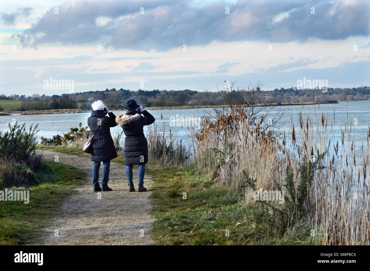 Due donne di bird-watching guardando oltre il fiume deben verso woodbridge suffolk England Regno Unito Foto Stock