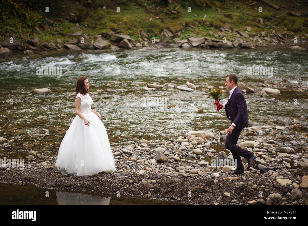Bella elegante sposi novelli a piedi vicino al fiume al di fuori Foto Stock