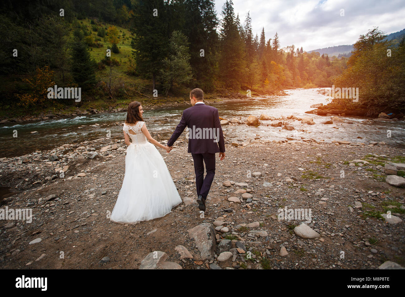 A tutta lunghezza vista dell'avvolgente sposa giovane sullo sfondo di la foresta e il fiume. Foto Stock