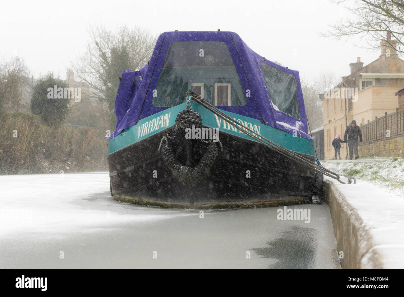 BATH, Regno Unito - 01 marzo 2018 strette barca sul canal congelati nella neve. Scena invernale lungo Kennet and Avon canal in bagno, con gente camminare sulla neve giorno Foto Stock