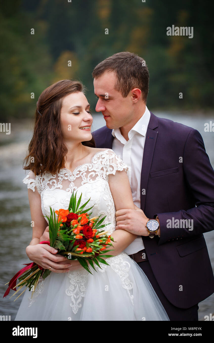 Il ritratto di abbracciando gli sposi a sfondo del fiume. Foto Stock