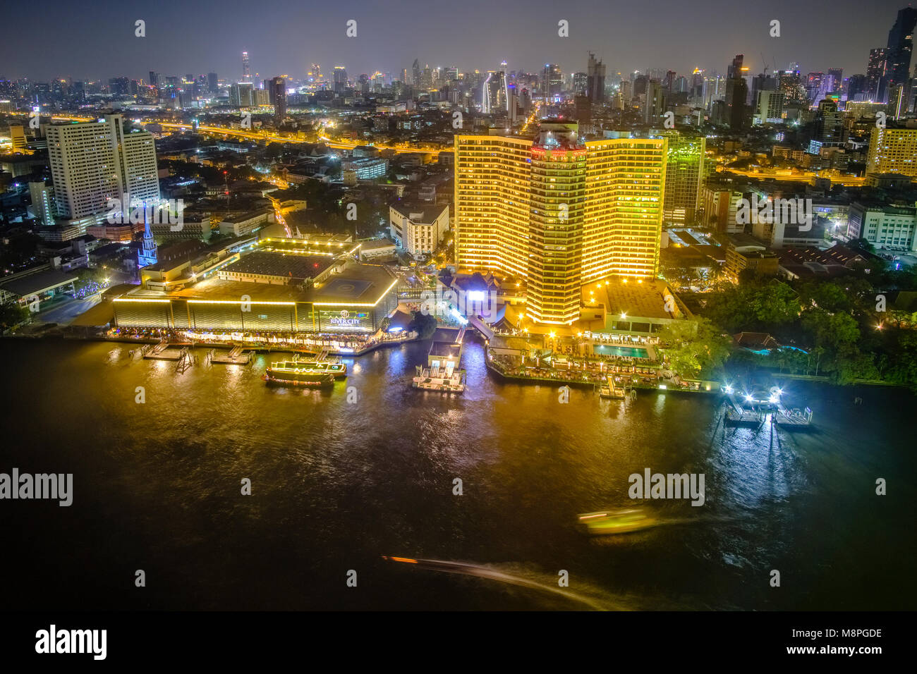 Panoramica vista aerea attraverso il Fiume Chao Phraya il Royal Orchid Sheraton Hotel e di edifici ad alta del centro cittadino e illuminata di notte Foto Stock