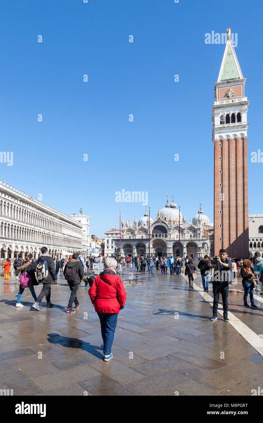 Turisti in Piazza San Marco, Piazza San Marco, su un soleggiato blue sky giorno alla fine dell'inverno, Venezia, Veneto, Italia con la Basilica di San Marco e della camma Foto Stock