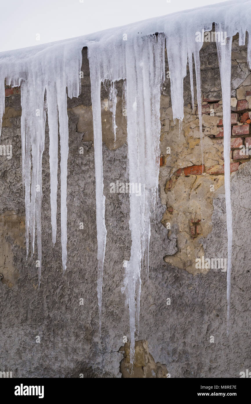 Enorme icicle pericolosa formazione sul tetto. Pericolo di fusione del ghiaccio sospesi dal tetto di un vecchio edificio in inverno Foto Stock