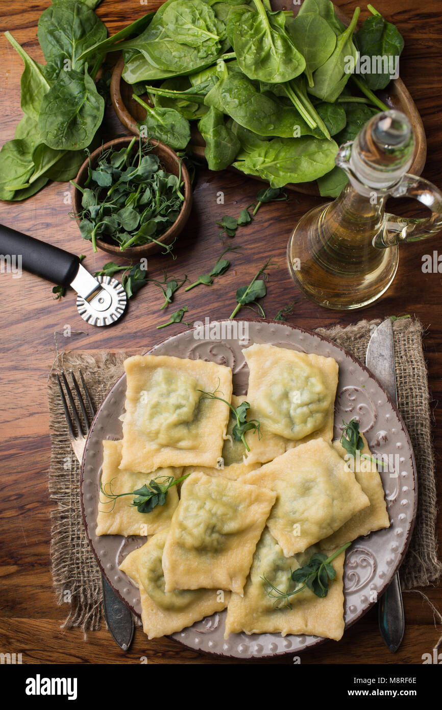 Pronti i ravioli in una piastra, spinaci, olio d'oliva in un vaso. Foto Stock