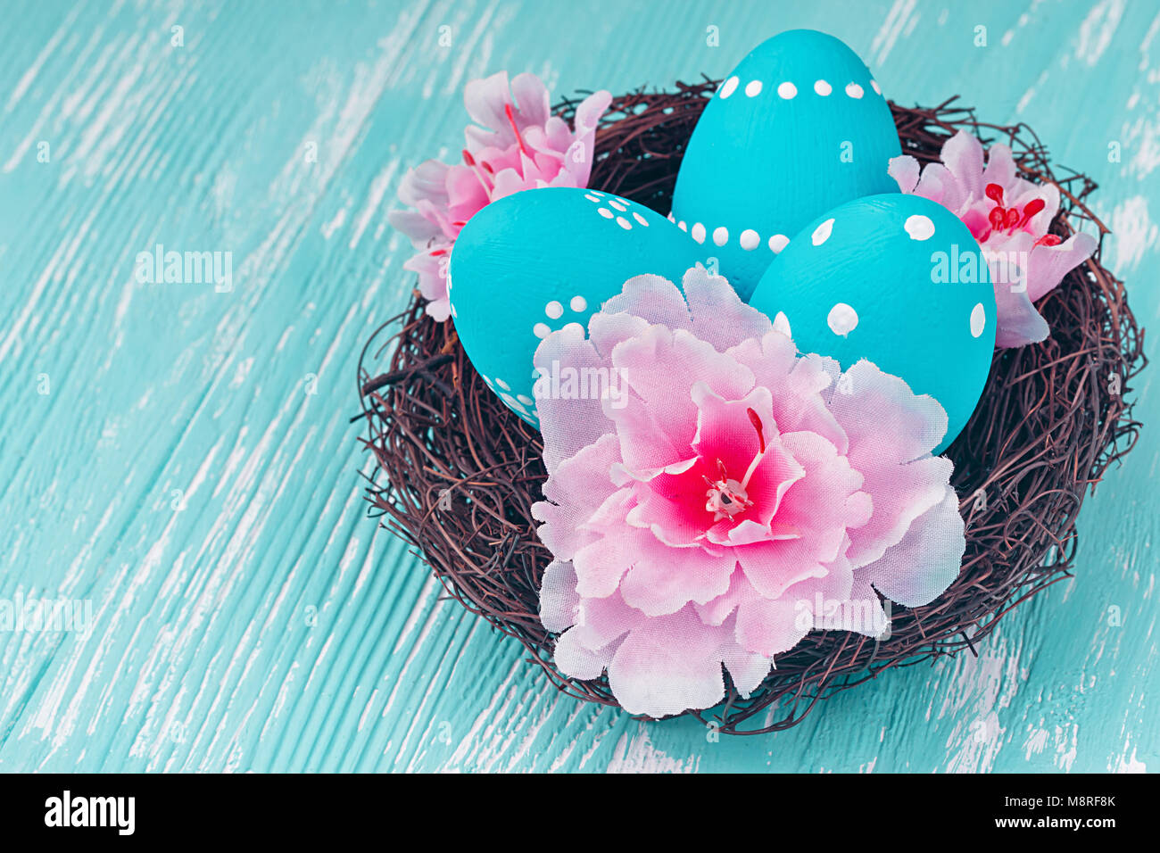 Blue uova di Pasqua nel nido su blu sullo sfondo di legno. Foto Stock