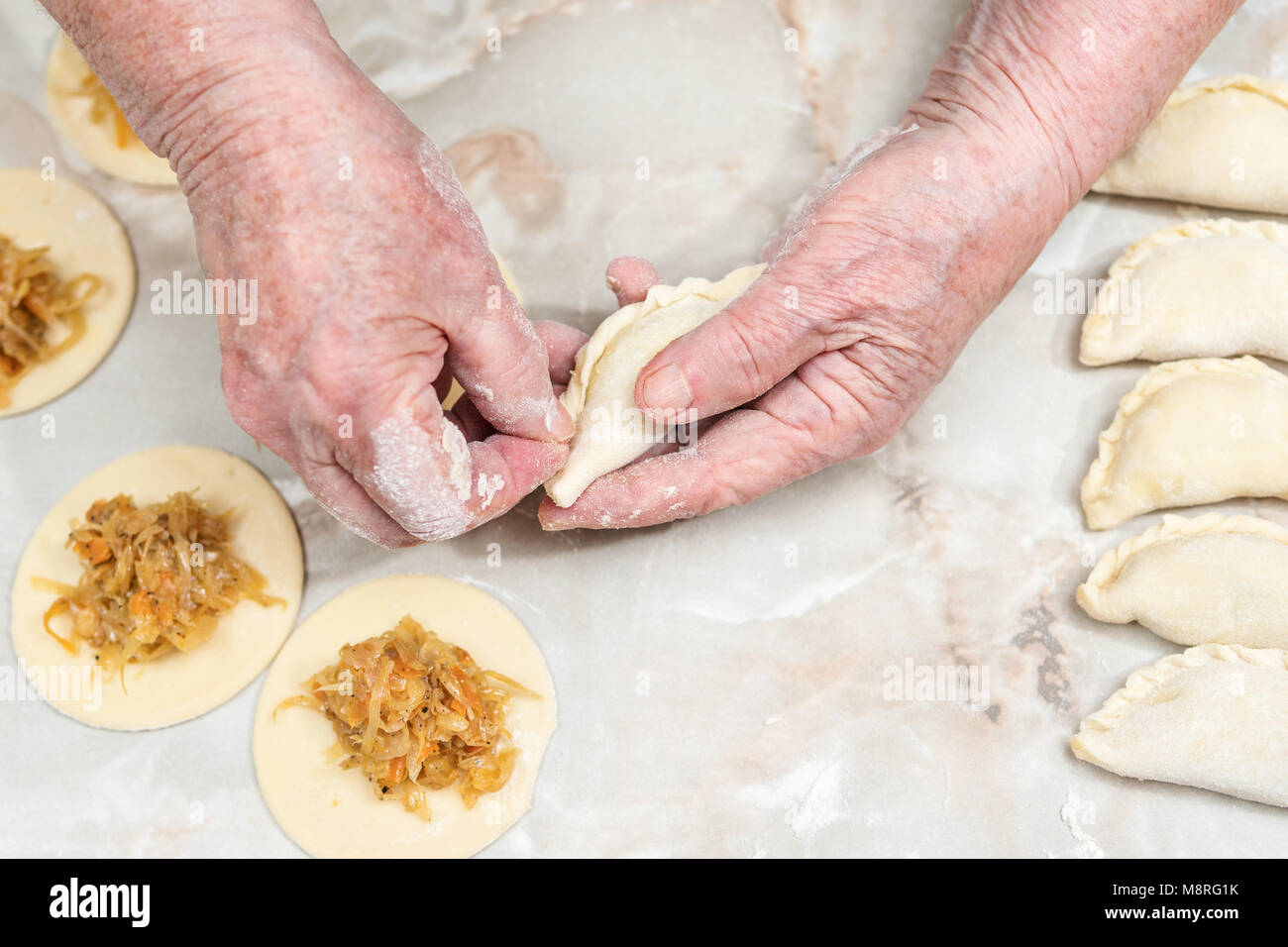 Le mani della donna di vecchio stampo vareniki con cavolo al di sopra della tabella Foto Stock