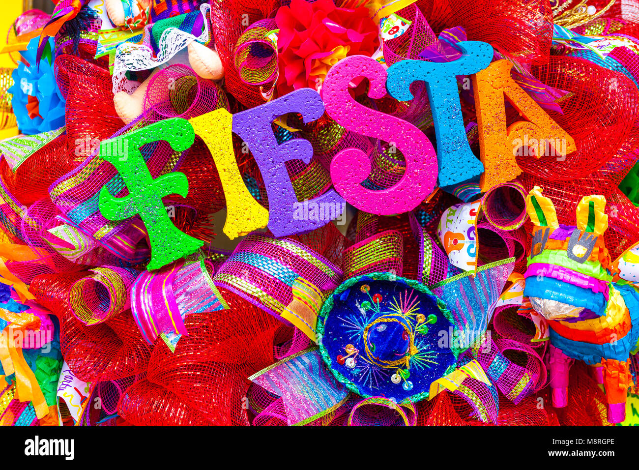 La parola "fiesta" scritto in schiuma colorate lettere sulla mescolanza multicolore decorata con glitter e piccolo sombrero Foto Stock
