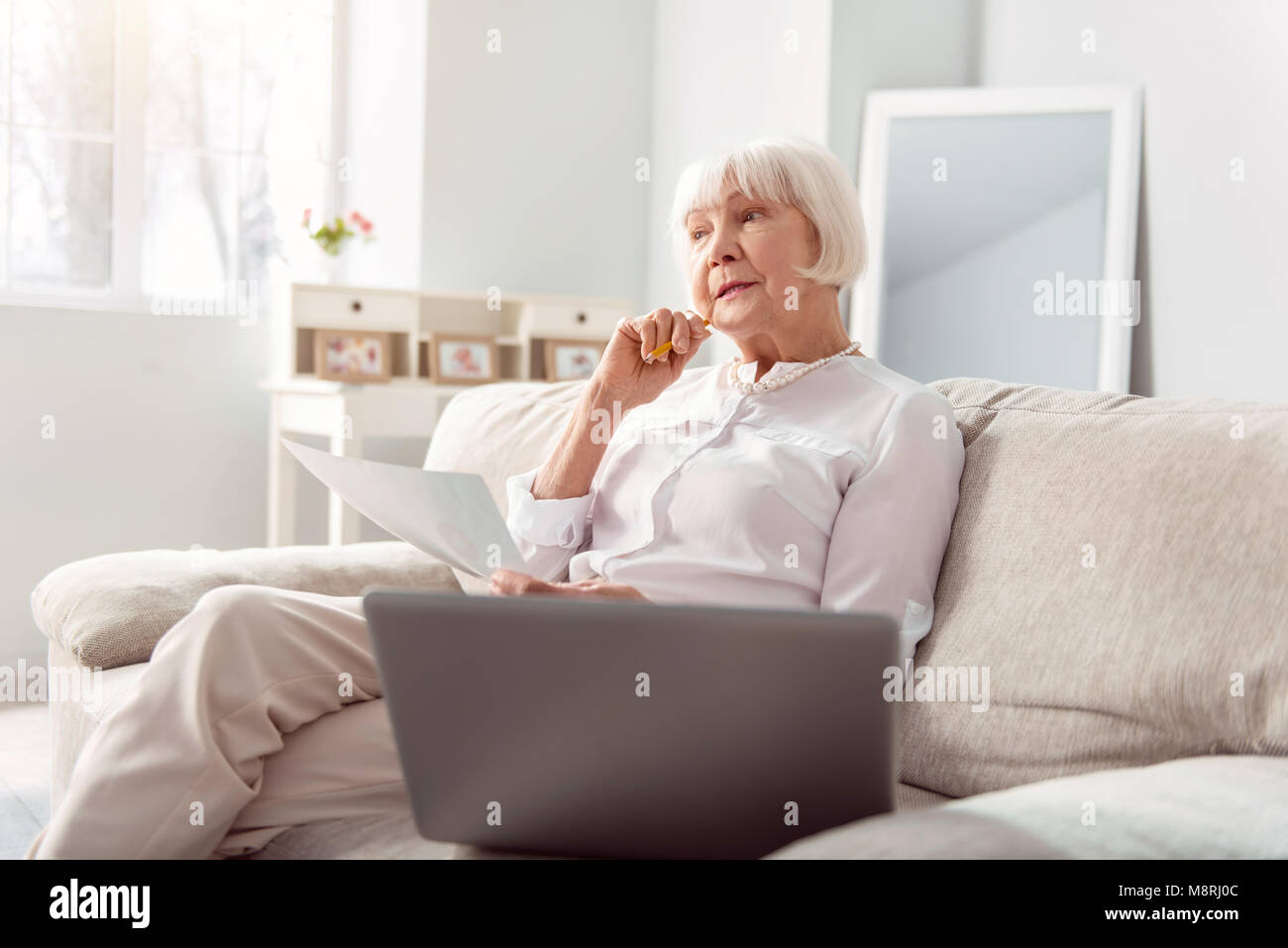 Piacevole donna anziana pensando di miglioramento dei progetti Foto Stock