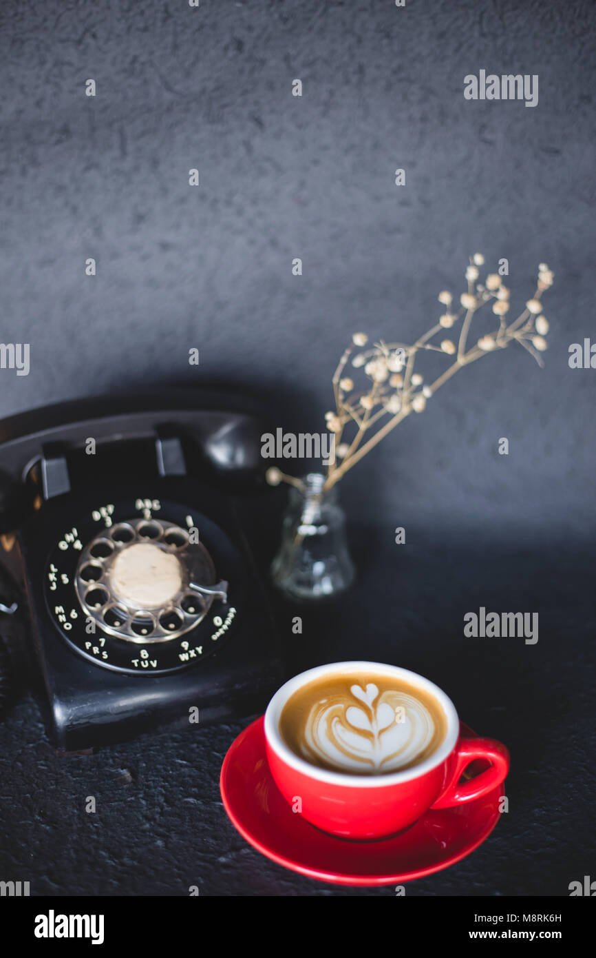 Latte art caffè con telefono retrò su nero dello spazio dei colori Foto Stock