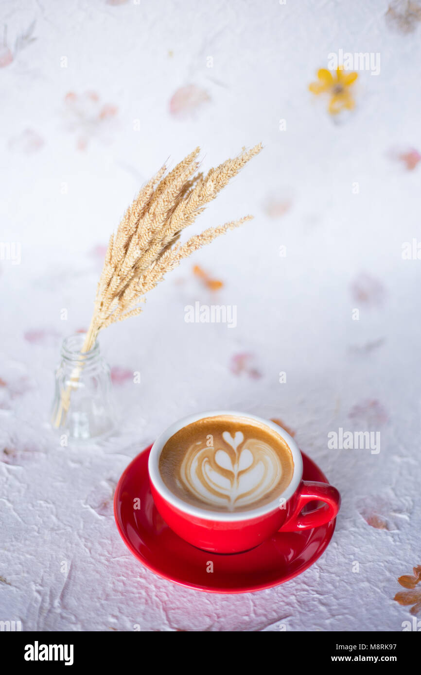 Un rosso tazza di caffè latte ' ' su vintage spazio con fiori secchi Foto Stock