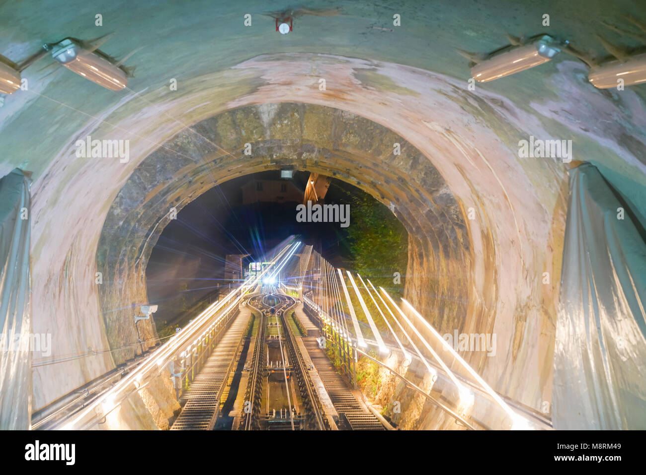 Corsa in funicolare, rotaie e tunnel lungo il tragitto nel tunnel con luci e sfocatura zoom sentieri di luce da distsnt fine. Foto Stock
