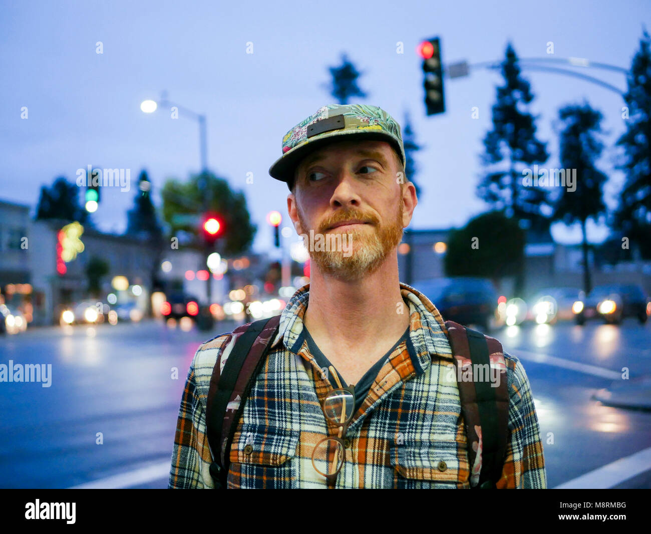 Uomo che guarda lontano mentre permanente sulla via della città al crepuscolo Foto Stock